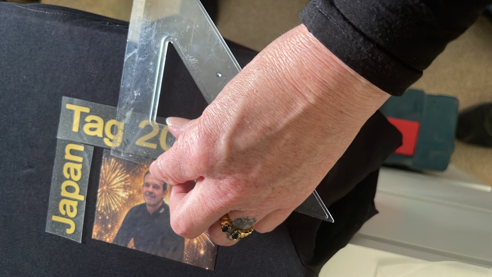 In het atelier wordt een transfer met foto en tekst uitgelijnd op een zwart shirt
